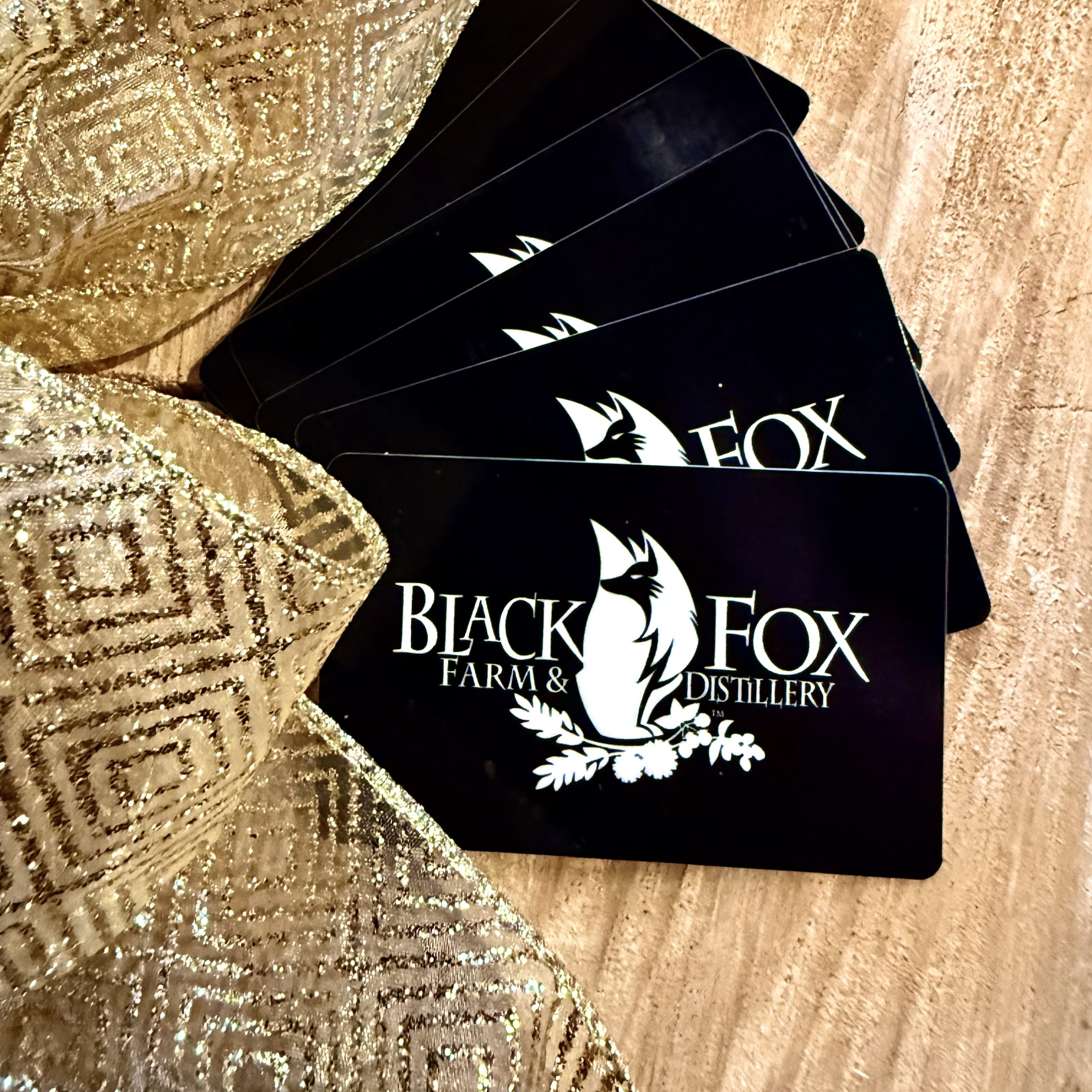 BlackFox_GiftCards_2025_IMG_5625 Black Fox Gift Cards overlaid with sparkly, holiday ribbon.